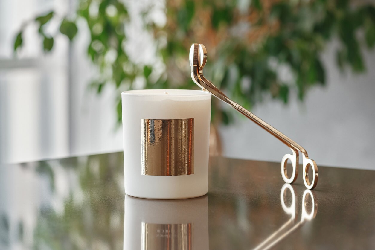 An image of a candle with a pair of wick trimmers on a wooden table, signifying the importance of wick trimming for a long-lasting candle.